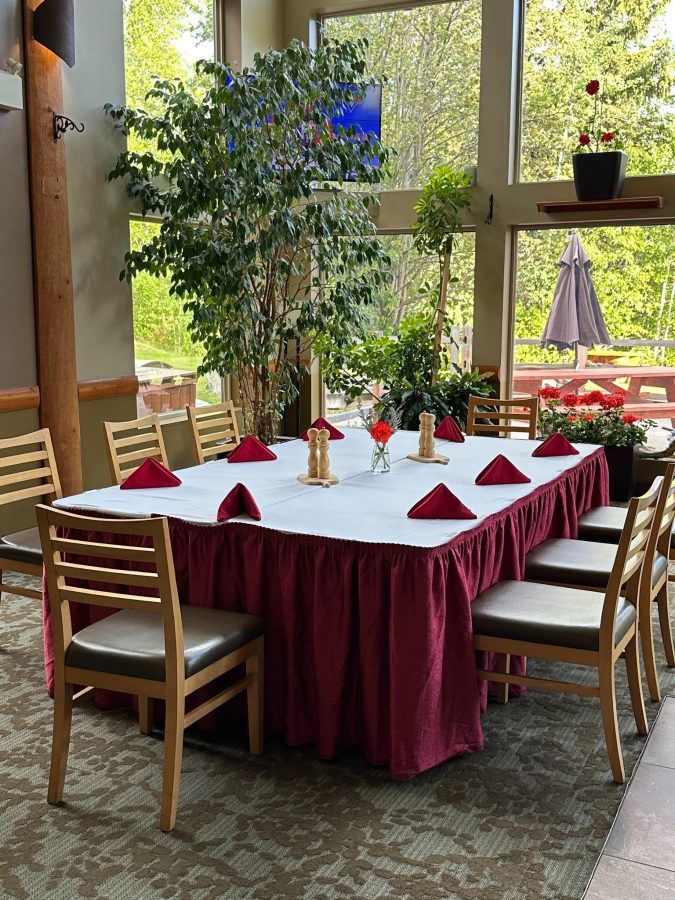 Dining table with red tablecloth and chairs set near large windows at Best Western Plus Valemount