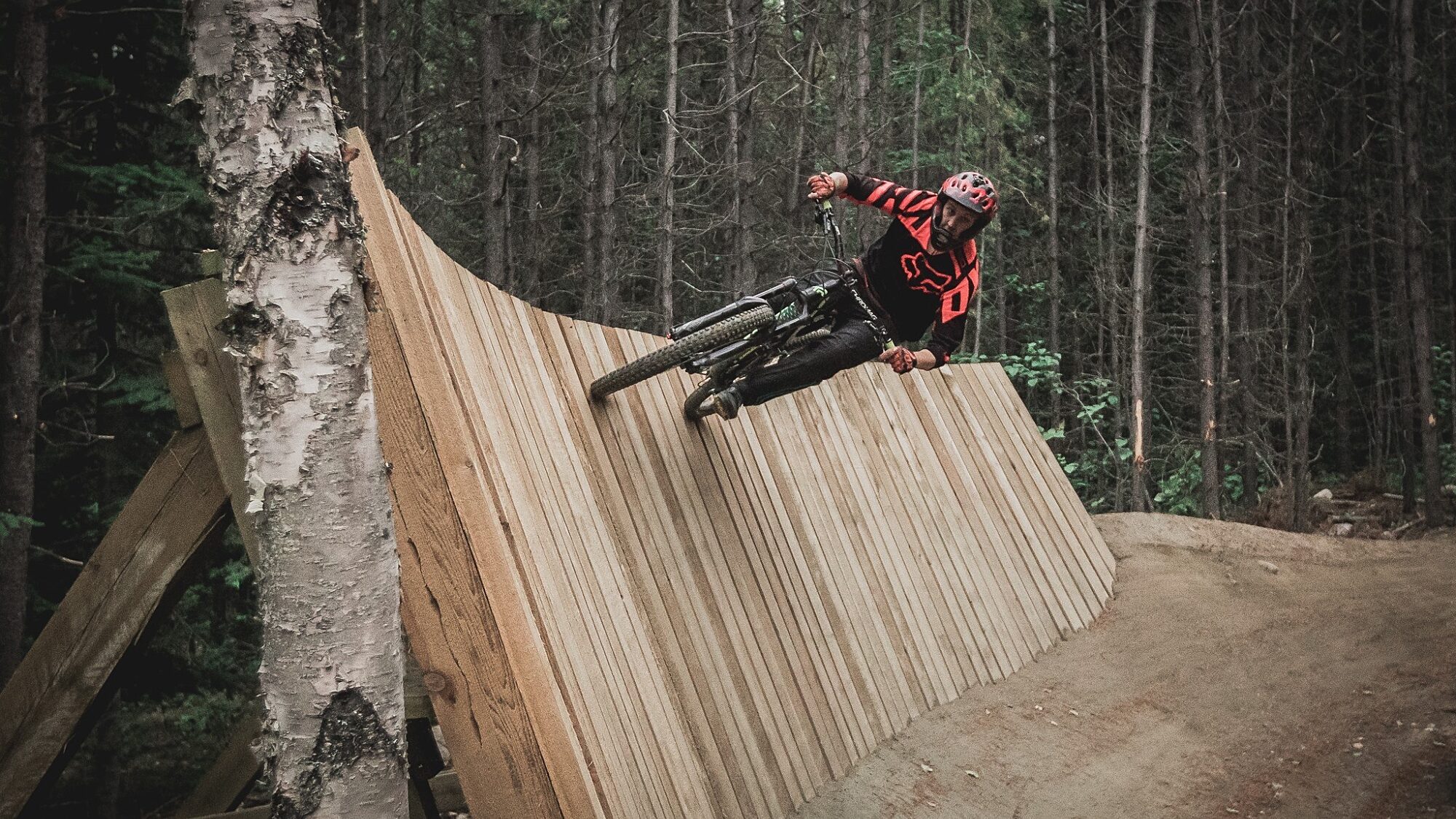 Mountain biker riding a wooden wall feature at Valemount bike park