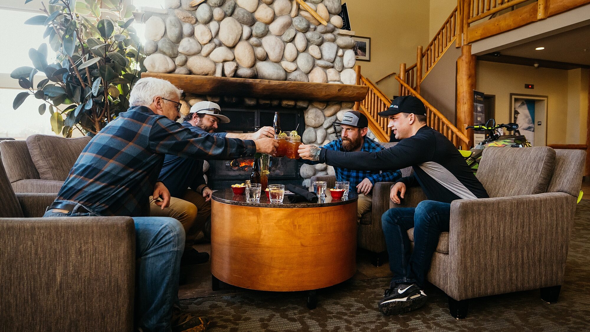 Guests toasting drinks while seated in a hotel lounge near a fireplace