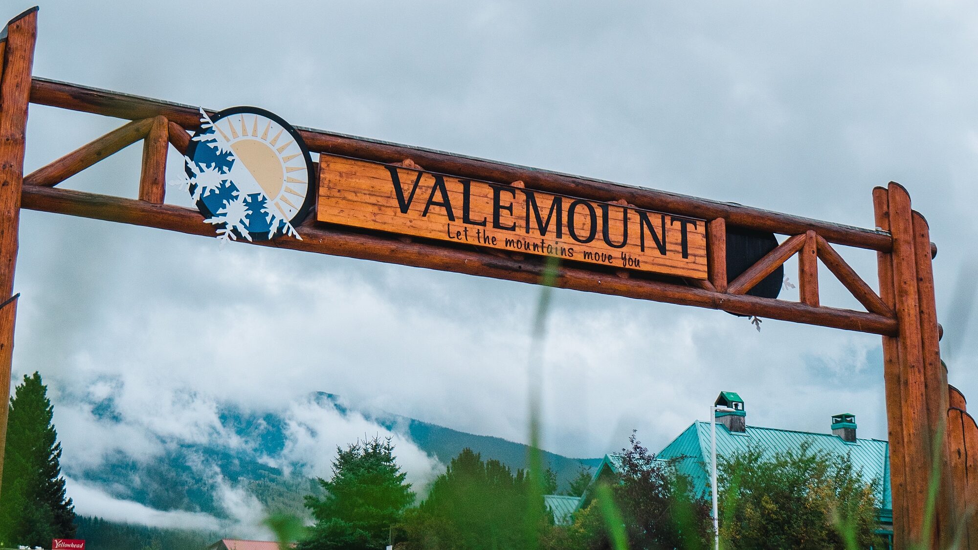 Wooden entrance sign reading “Valemount” with mountains in the background