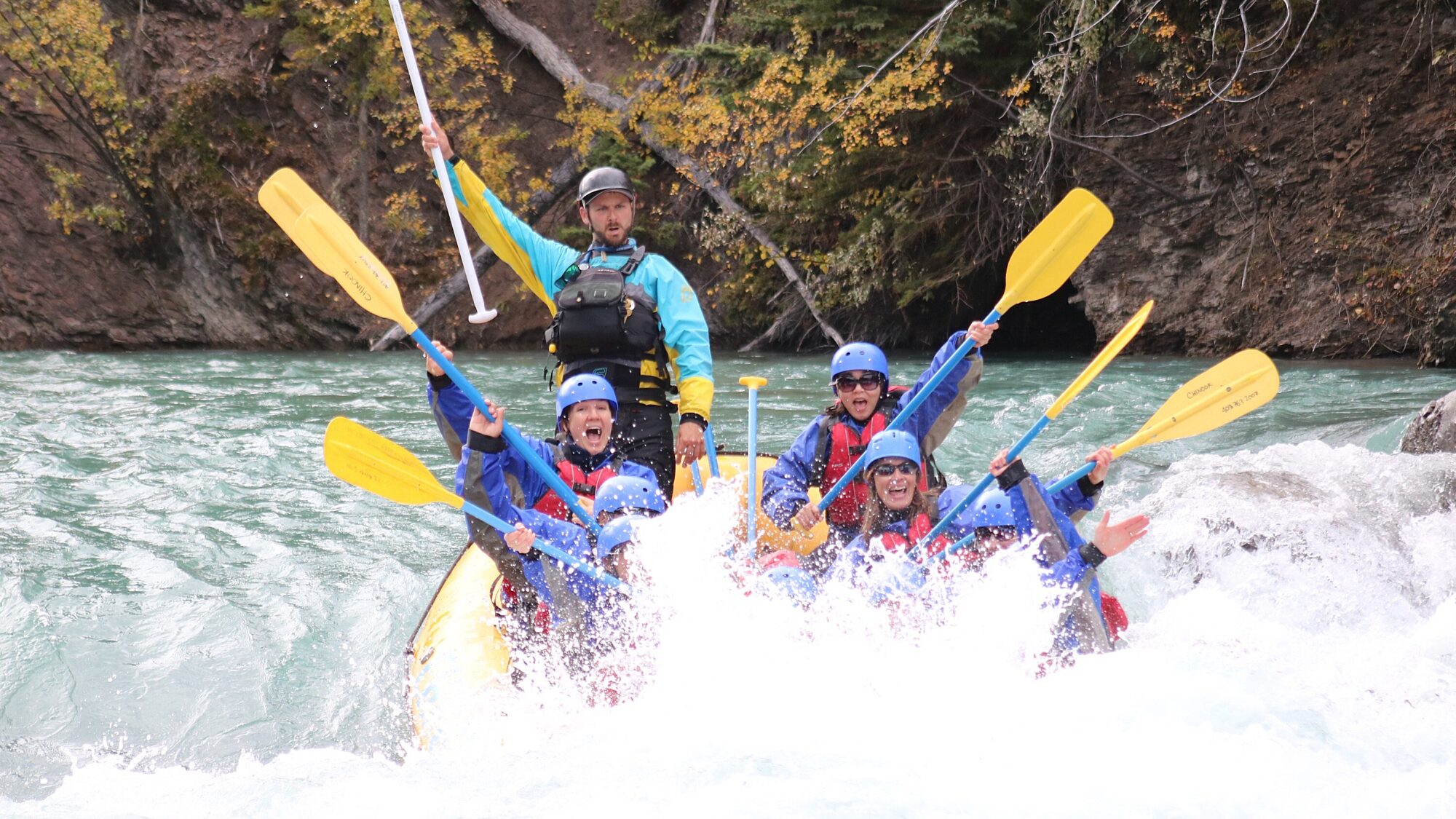 Rafters paddling through whitewater rapids on a mountain river in Valemount