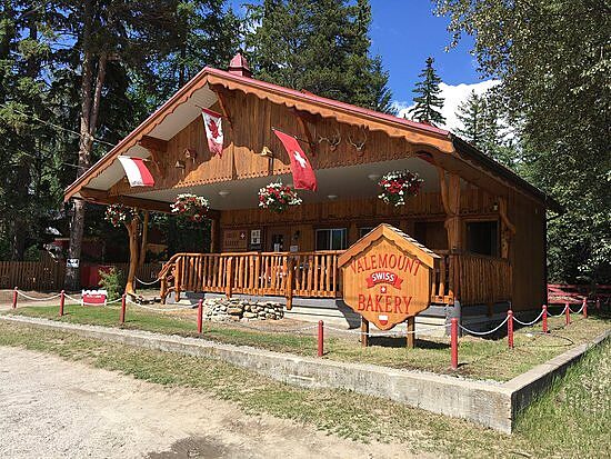 Valemount Swiss Bakery building with wooden exterior, flower baskets, and Canadian flags