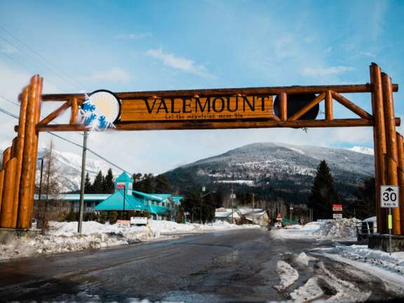 Wooden entrance arch reading “Valemount” over a snow-covered roadway