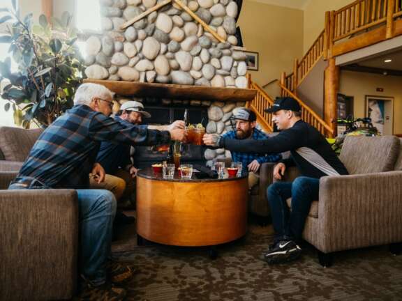 Group of guests seated around a table toasting to drinks in the Cranberry Lounge at Best Western Plus Valemount