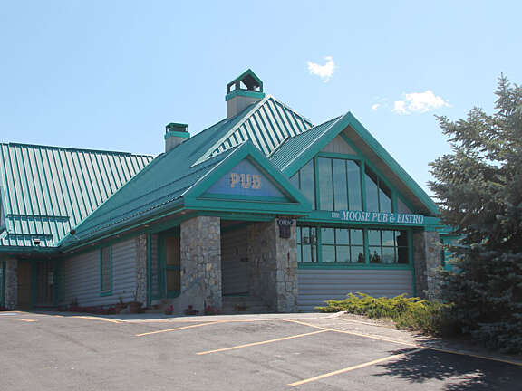 Exterior of The Moose Neighborhood Pub with parking area and peaked roof in Valemount