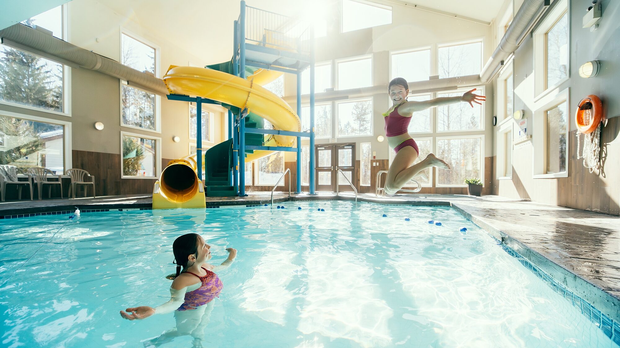 Guest jumping into an indoor pool with water slide at Best Western Plus Valemount