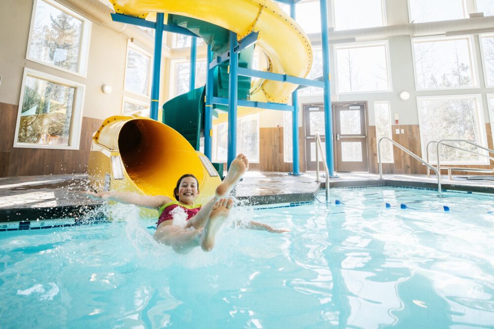 Guest exiting a yellow water slide into the indoor pool at Best Western Plus Valemount